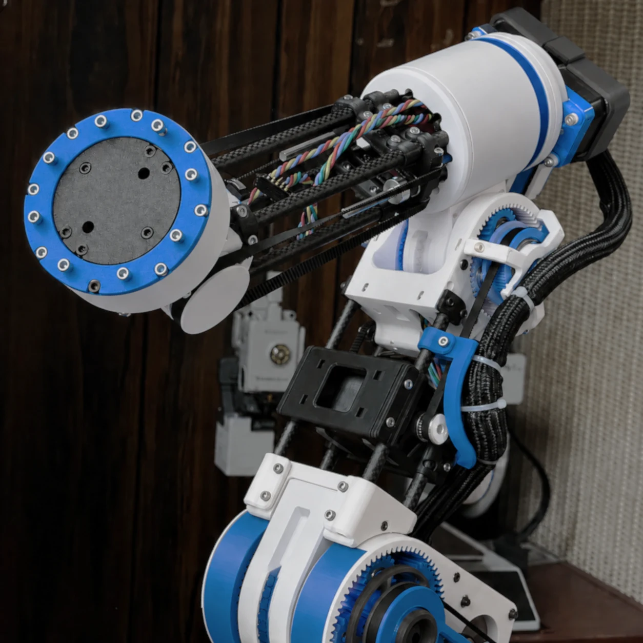 Blue, white, and black 3D-printed robotic arm with exposed gears and wiring